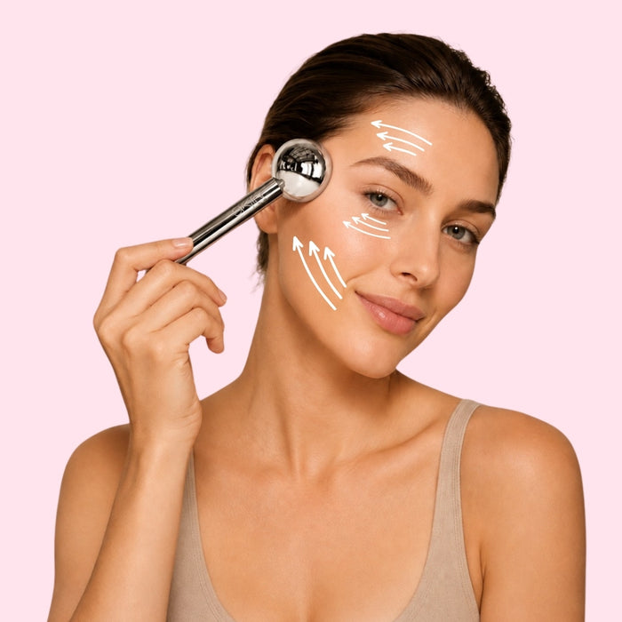 Femme appliquant le Cryo Ice Glow sur sa pommette, flèches blanches indiquant le sens du massage sur le front, la joue et la mâchoire, fond rose