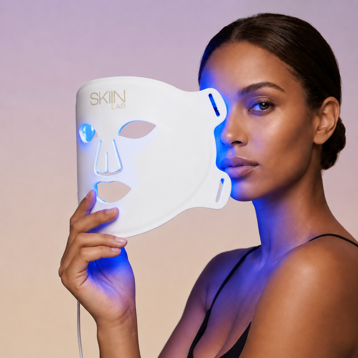 Femme tenant le masque LED visage Lumina 630 avec la lumière bleue allumée sur la peau