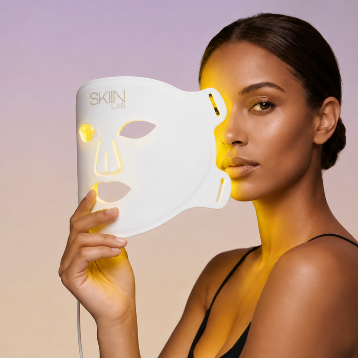 Femme tenant le masque LED visage Lumina 630 avec la lumière jaune ambre allumée sur la peau